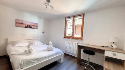 a bedroom with a bed with a desk and a swan on it at Le Zen in Eguisheim