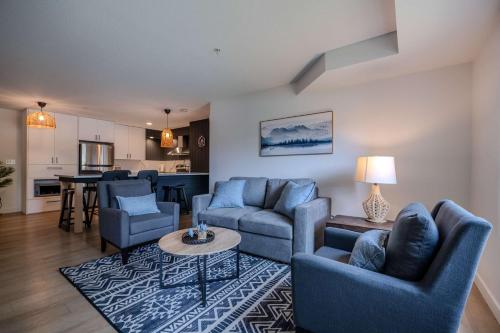 a living room with blue couches and a kitchen at The Beach Point - Ground Floor BBQ in Invermere