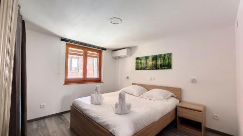 a bedroom with a bed with white sheets and a window at Le Nature in Eguisheim