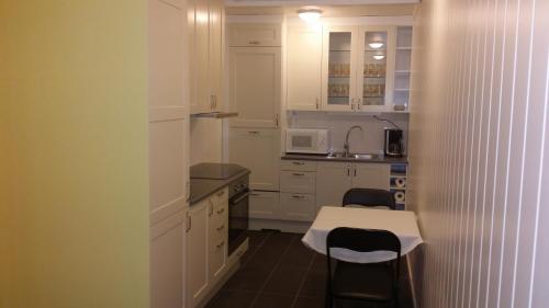 a kitchen with white cabinets and a table and chairs at Polar Hotel Oteren in Oteren