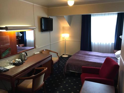a hotel room with a bed and a desk and a mirror at Polar Hotel Oteren in Oteren