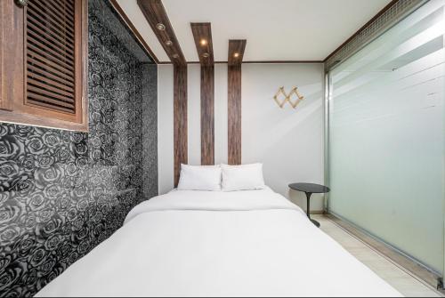 a bedroom with a white bed and a black wall at 호텔 휴 in Pup'yŏng-yŏk