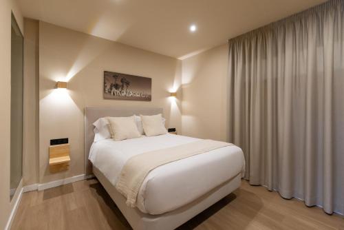 a bedroom with a large white bed and a window at Arena Málaga Suites in Málaga