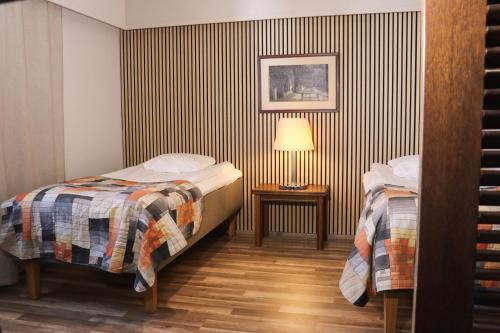 ein Zimmer mit zwei Betten und einer Lampe auf einem Tisch in der Unterkunft Hotel Sommelo in Kouvola