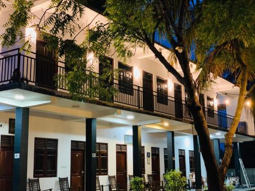 a building with a balcony with chairs and a tree at Quench Inn in Ampara