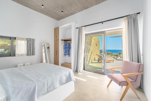 a bedroom with a bed and a chair and a window at Gray and Blue in Andros