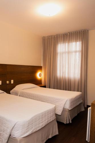 a hotel room with two beds and a window at Hotel Kennedy in São José