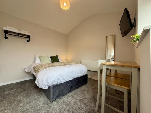 a bedroom with a bed and a desk and a television at The Den- Cosy Studio in Dowlais