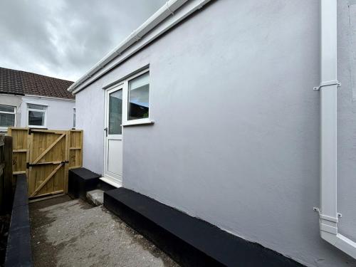 a white building with a door and a window at The Den- Cosy Studio in Dowlais
