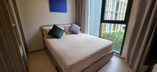 a bed with two pillows sitting in front of a window at The Rock Condo Central Phuket "Min-1 week" in Ban Rangeng