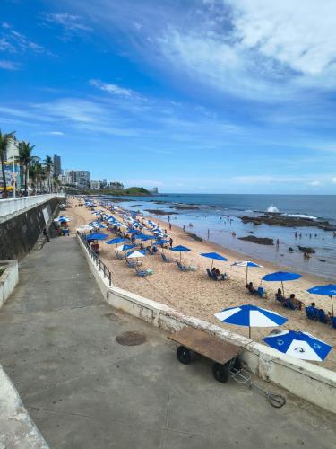 a beach with many umbrellas and people in the water at Aconchego das Borboletas in Salvador