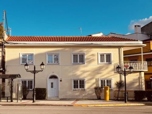 a white house with a red roof on a street at La Villa Toledana in Cabañas de la Sagra