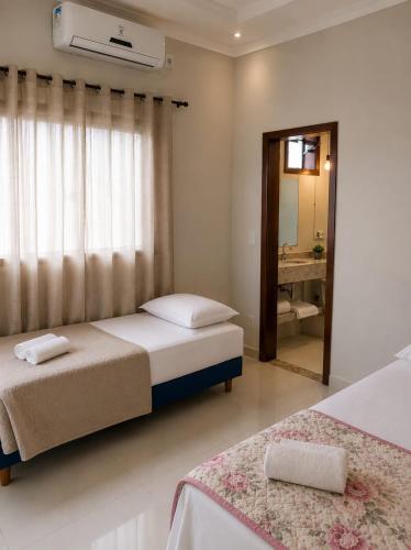 a bedroom with two beds and a window and a mirror at Pousada Emanuel in Paracatu