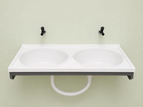 a white sink on a white wall with two pulls at Pousada Emanuel in Paracatu