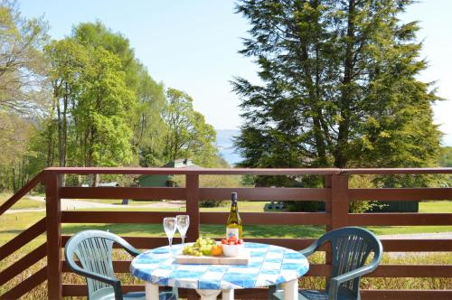 a table with a bottle of wine and a bowl of fruit at Loch View Lodge in Dunoon