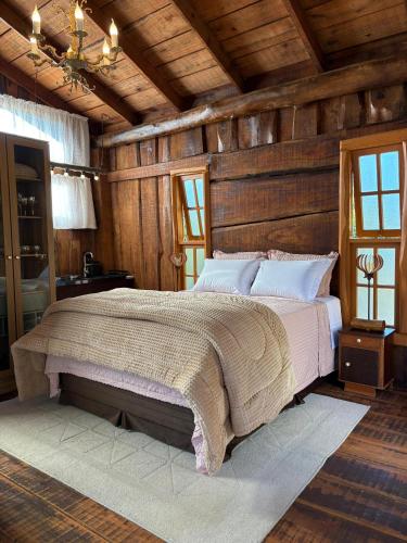a bedroom with a large bed with wooden walls at Chalé Do Lago in Garibaldi