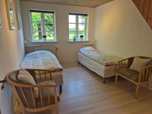 a bedroom with a bed and a chair and two windows at Tranum B&B in Brovst