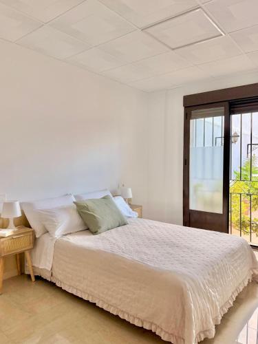 a white bedroom with a bed and a window at Casa Placeta Serna in Vélez-Rubio