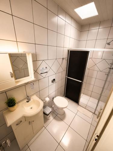 a white bathroom with a toilet and a sink at Pousada Arcanjo Rafael in Urubici