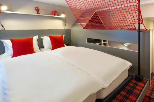 a bedroom with a large white bed with red pillows at RockyPop Chamonix - Les Houches in Les Houches