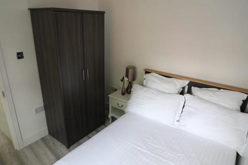a bedroom with a bed with white sheets and a black closet at Comfy Guest suite in Dartford