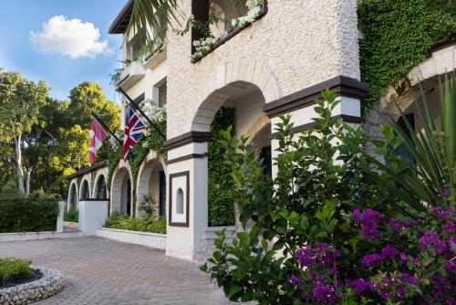 a building with two flags and purple flowers at Blue Monkey Hotel & Beach Club in Saint James