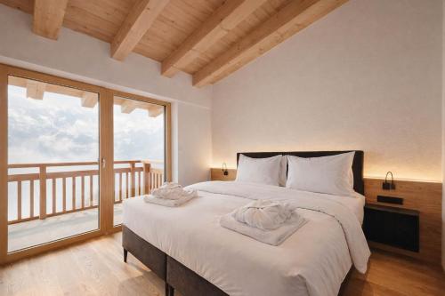 a bedroom with a large bed and a large window at SKYLINE Chalet - Two-Level Penthouse with Private Whirlpool in Mühlen