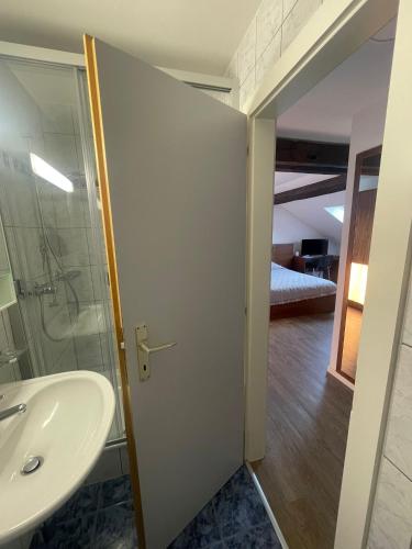 a bathroom with a sink and a glass shower door at Auberge de la Charrue in Romanel-sur-Lausanne