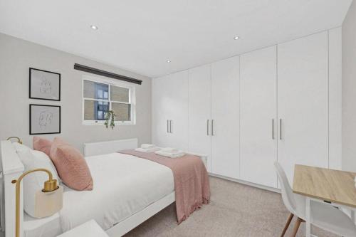 a white bedroom with a bed and a desk at Flat in Lambeth in London