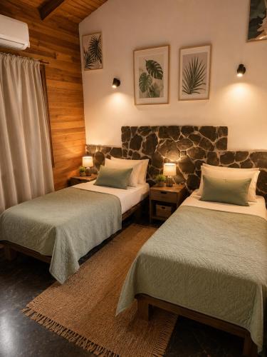 a bedroom with two beds and a stone wall at Anam Apartments in Santa Teresa Beach