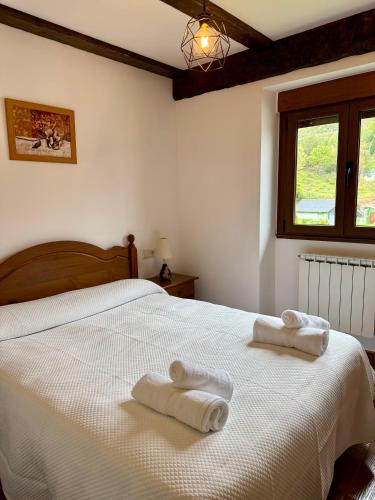 a bedroom with a white bed with towels on it at Rincón de Laciana in Caboalles de Abajo