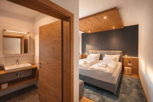 a bedroom with a bed with a sink and a mirror at RUHESTUBE - Design Apartment with Balcony in Fügen