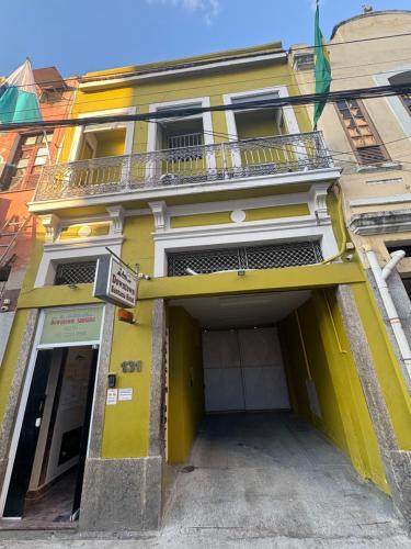 a yellow building with a door and a balcony at Downtown Santana Hotel in Rio de Janeiro