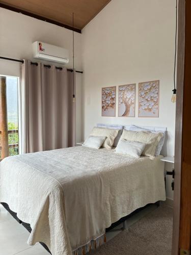 a white bedroom with a large bed with white sheets at Casa Águas Claras in Palmeiras