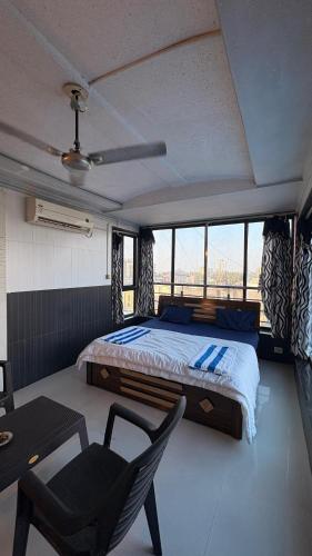 a bedroom with a bed and a table and a chair at Rooftopwaves penthouse in Daman
