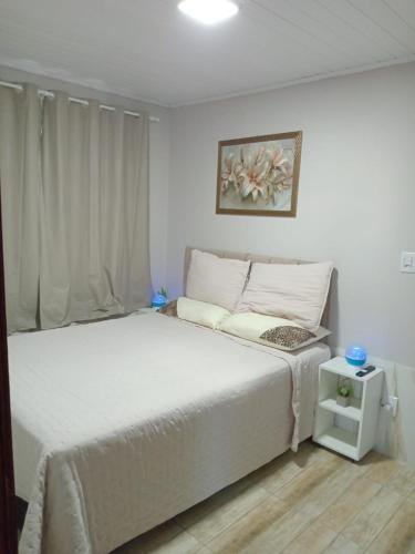 a bedroom with a white bed and a window at Aluguel casa azul in Capão da Canoa