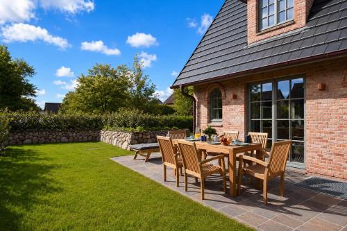 a patio with a table and chairs on a lawn at Die Perle von Wenningstedt in Braderup