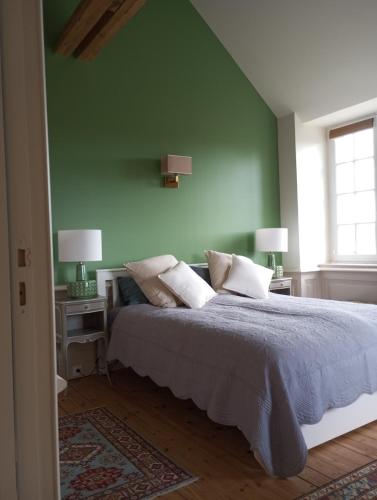 a green bedroom with a bed with pillows and two lamps at Château des Boulais Suite in Saint-Martin-le-Bouillant