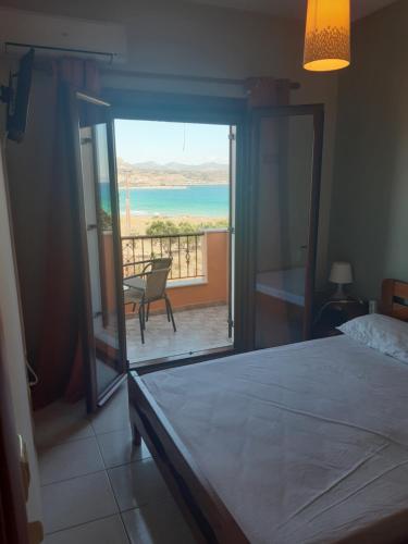 a bedroom with a bed and a view of the ocean at Savvas Apartments in Plytra