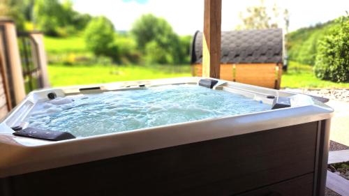 a hot tub with water in it on a patio at Gîte & Spa PRIVÉ "La Colline de Laveline" Proche GÉRARDMER in Laveline-du-Houx