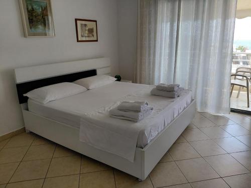 a white bed in a bedroom with a window at Monda Apartments Dhermi in Dhërmi