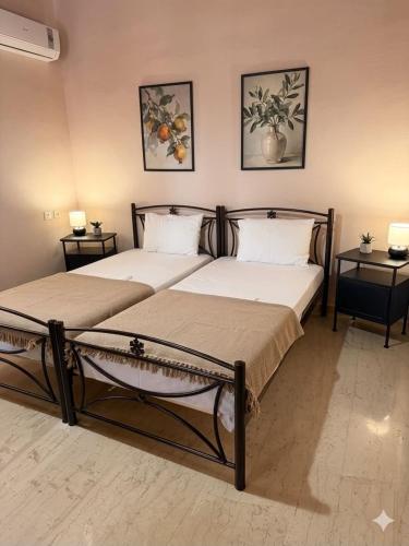 two beds in a room with two side tables at ST-Home in Loutsa
