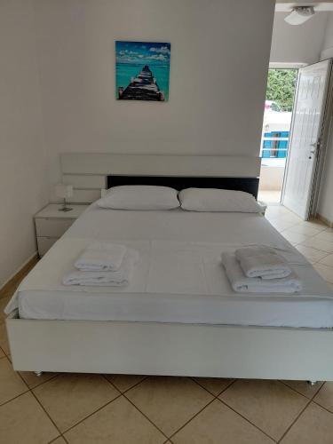 a white bed in a white room with towels on it at Monda Apartments Dhermi in Dhërmi