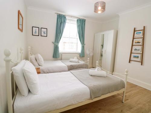 two beds in a bedroom with blue curtains at Springfield in Fakenham
