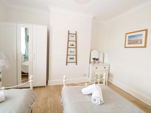 a white bedroom with a bed and a mirror at Springfield in Fakenham