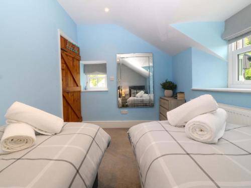 two beds in a room with blue walls and a mirror at Old Chapel House in Llanfairfechan