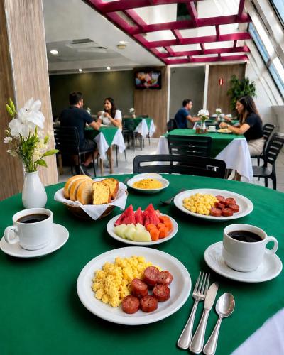 a green table with plates of breakfast food on it at Hotel Nacional Arapiraca in Arapiraca