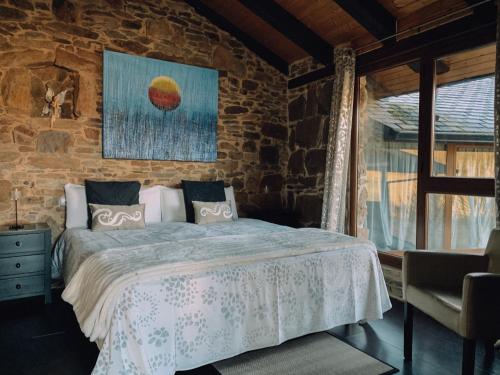 a bedroom with a bed and a stone wall at Alojamiento Luz de Hadas in Sampil