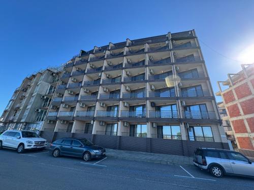 a tall building with cars parked in a parking lot at Infinity Sea View Studio in Pomorie