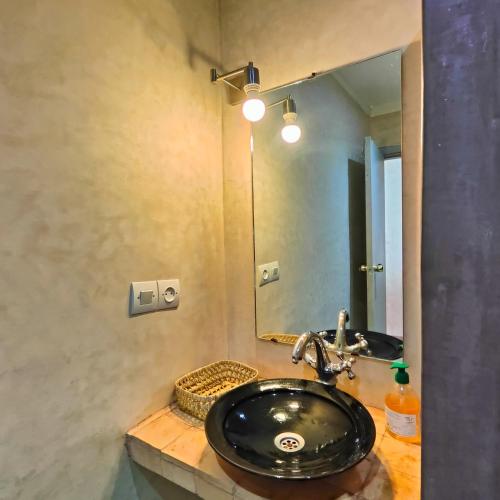 a bathroom with a black sink and a mirror at Darna in Marrakesh